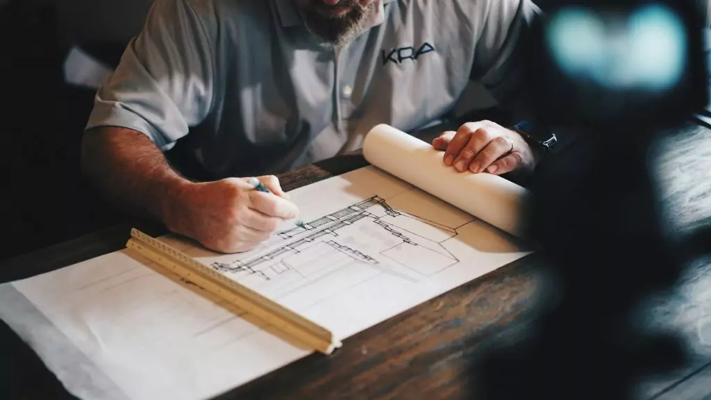 Architekt sitzt über einem Plan und macht Notizen