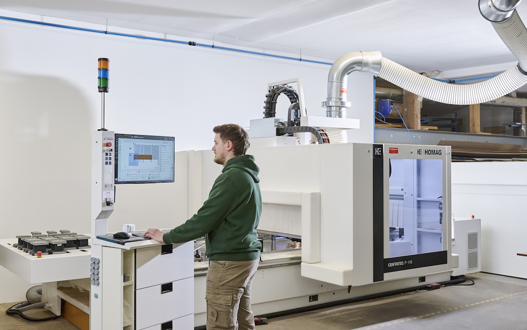Projektmitarbeiter bedient am Computer eine Maschine